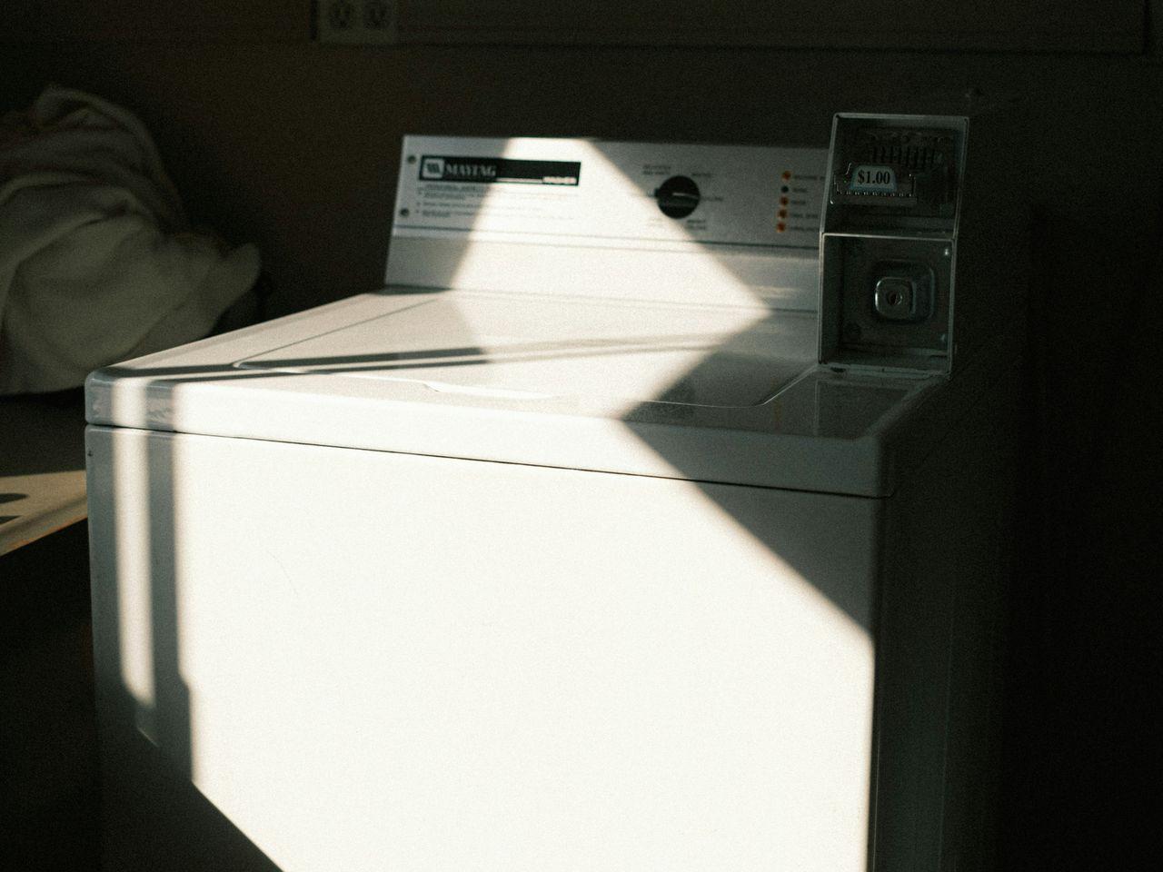Waschmaschinen und Wolle vertragen sich nicht immer gut. Es kommt auf die Einstellungen an. Ein Analogfoto einer Waschmaschine im Sonnenlicht