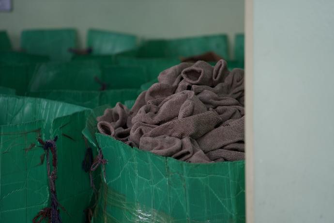 Zur Fertigstellung der Produkte wird alles erneut gewaschen Ein Haufen von Socken liegt in einem grünen Behälter