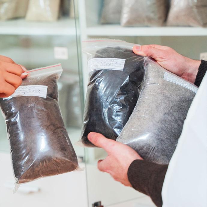 Yakwolle nach der Reinigung und Enthaarung Drei Plastiktüten mit roher Wolle werden in einem Labor hochgehalten