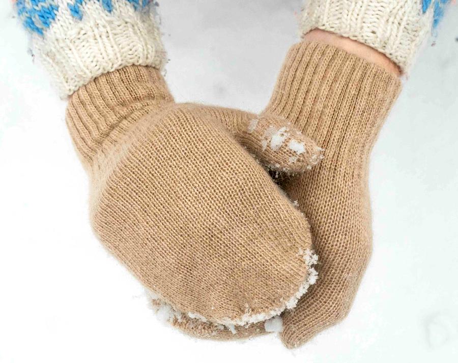 Beige camel wool mittens clench a snowball