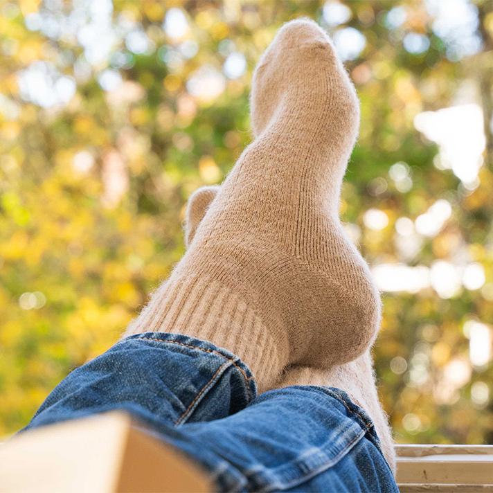 Bequeme Kamelwoll-Socken, die gemütlich an den Füßen eines Erwachsenen getragen werden.