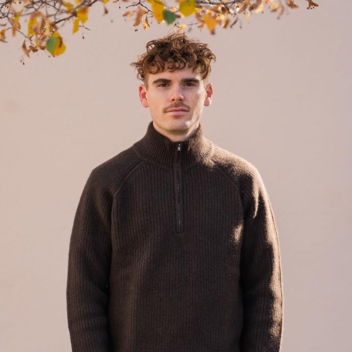 Man wears thick pullovers in dark yak wool under autumn leaves.