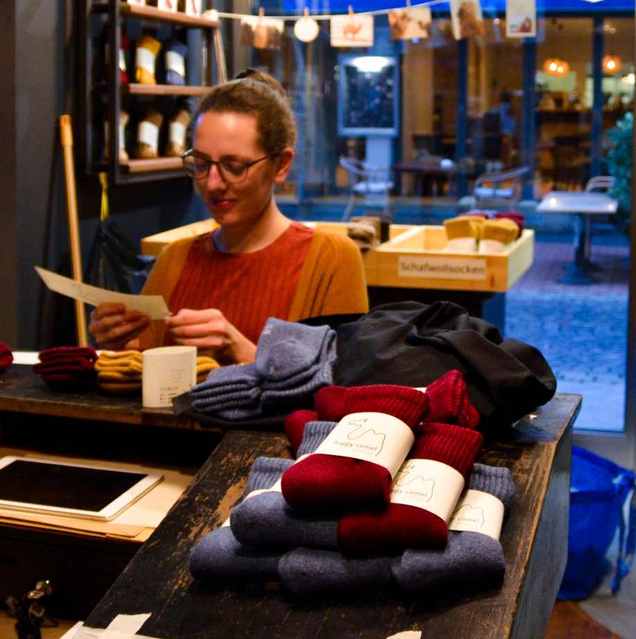 Eine Frau in orangenem Outfit packt bunte Wollsocken