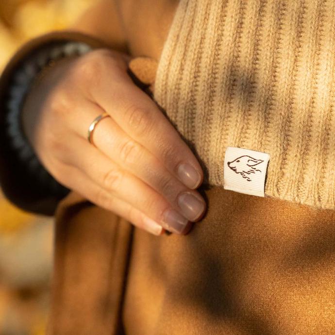 Jeder Schal kommt mit einem kleinen steppenstrolch Logo Finger halten einen Wollschal mit einem kleinen steppenstrolch Logo drauf