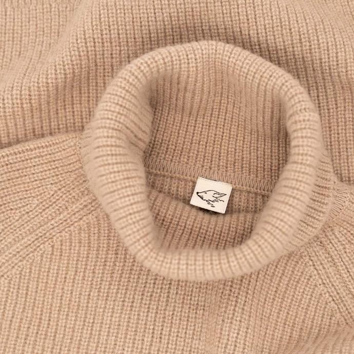 Immer einen steppenstrolch dabei Kragen eines beigen Rollkragenpullover mit steppenstrolch Logo im Nacken